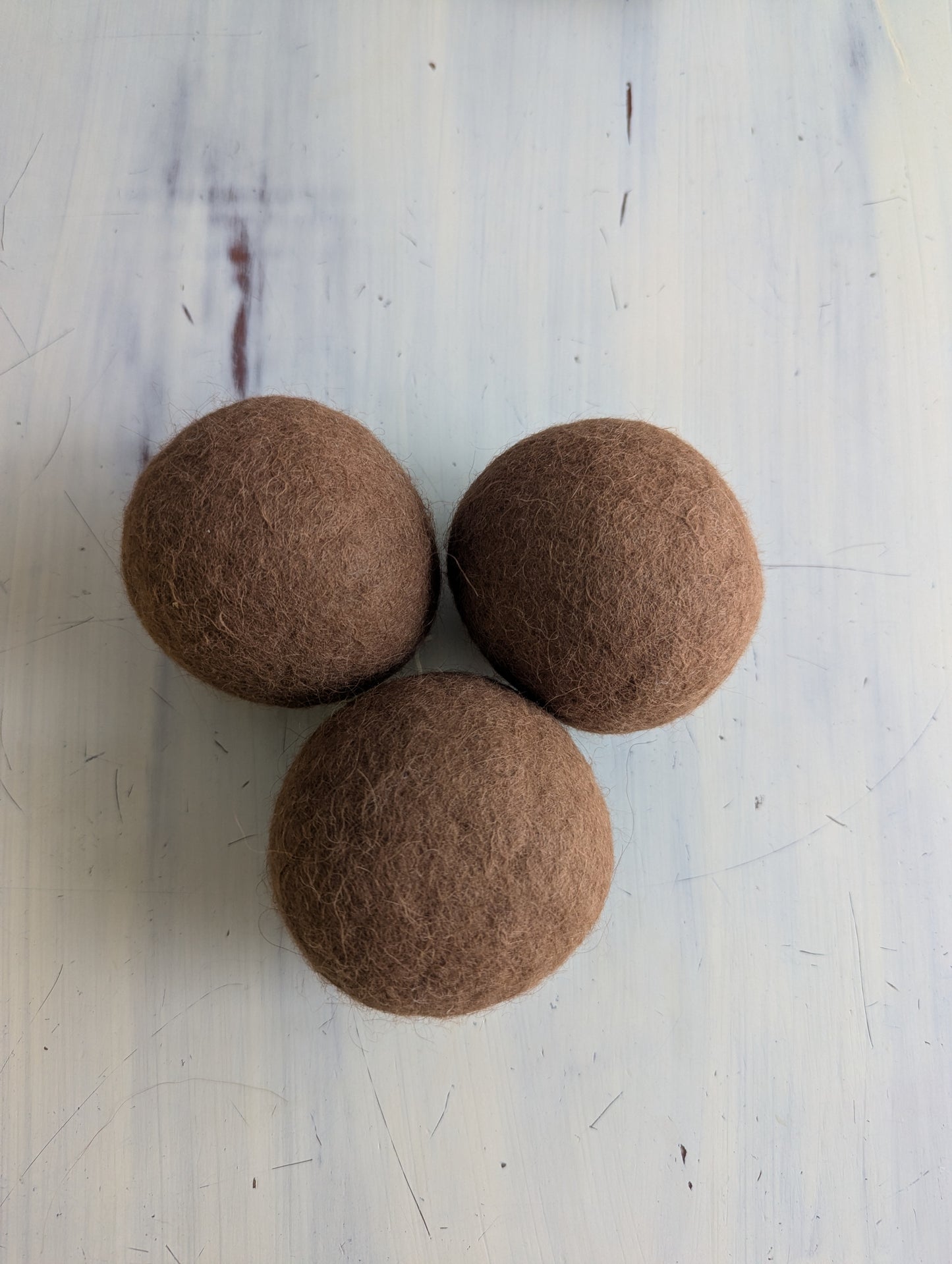 Three brown felt balls on a light gray surface