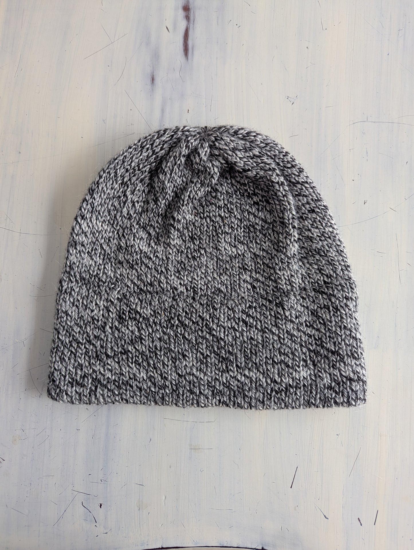 Knitted beanie on a textured white surface