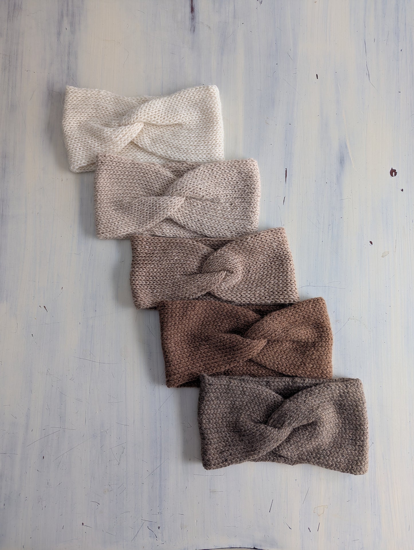 Set of five knitted headbands in various colors on a light wooden surface