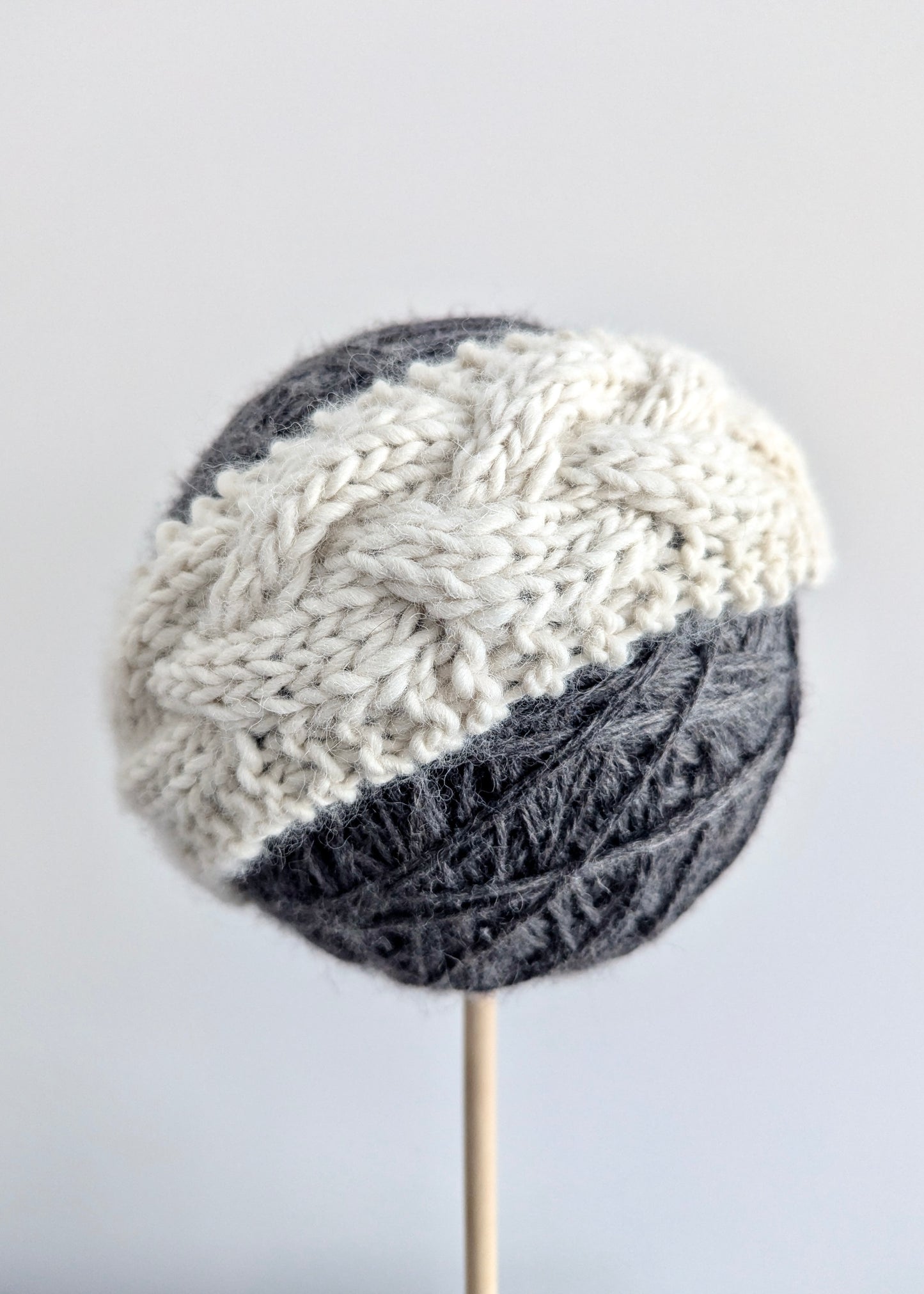 Knitted headband with gray and white pattern on a light gray background