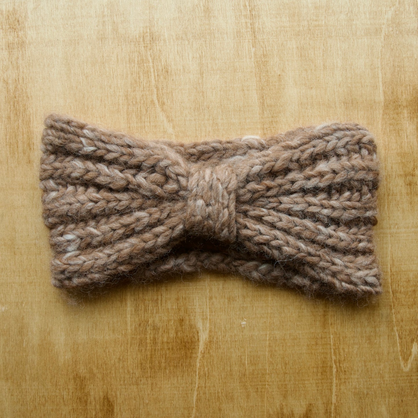 Brown knit headband with brioche ribbing over a wood background