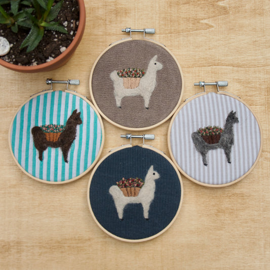 Embroidered alpaca collection with flowers, featured in a 4 inch wood hoop, on a beige background.