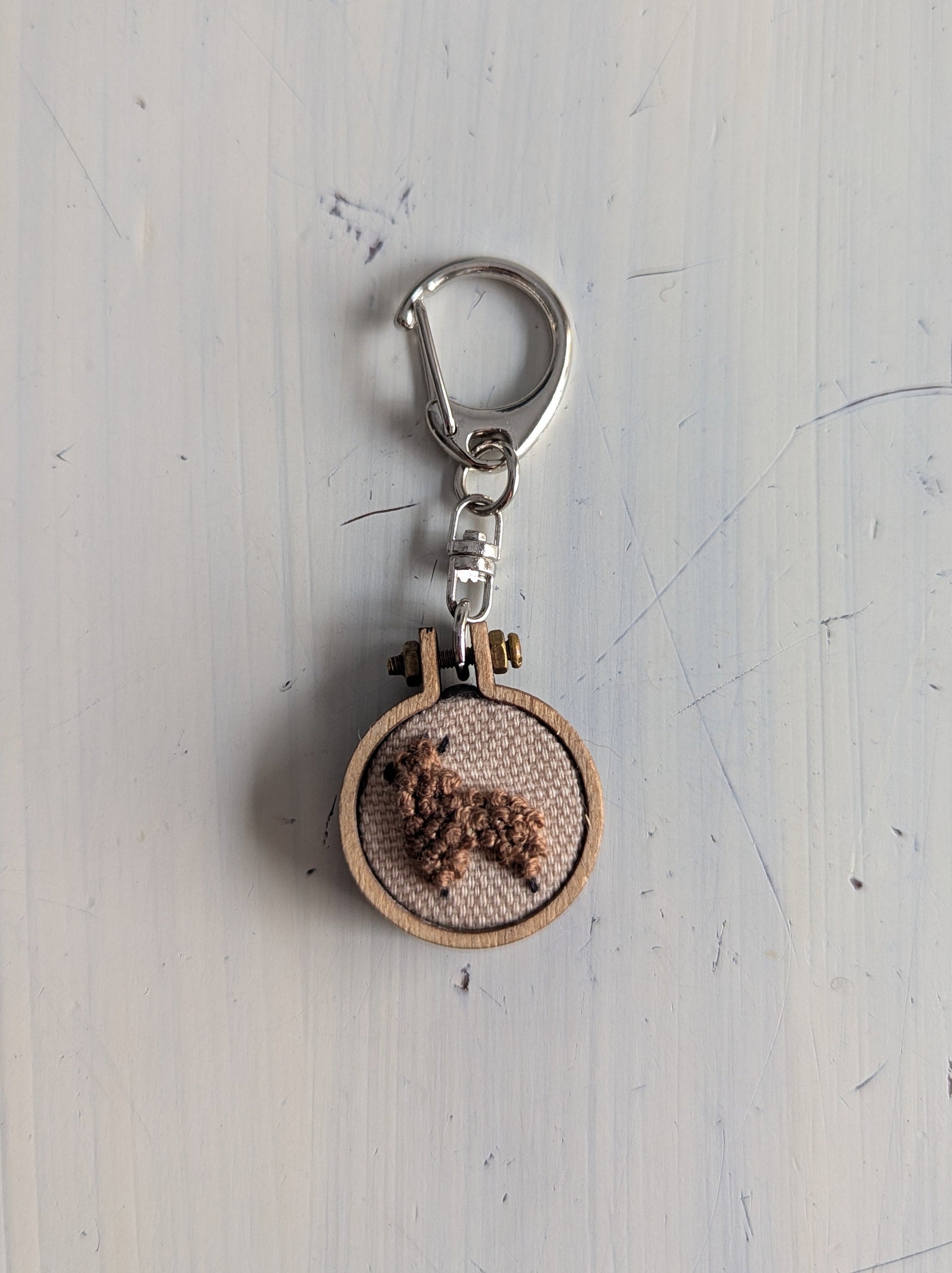 Keychain with wooden circle and metal clip on a light gray background