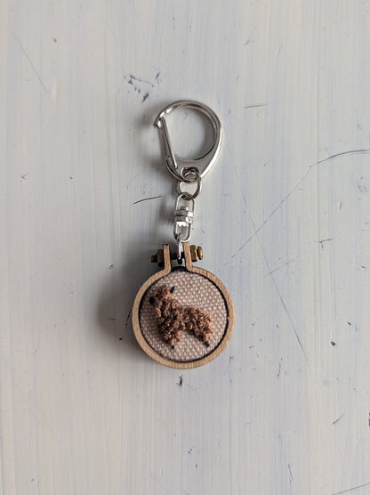 Keychain with wooden circle and metal clip on a light gray background