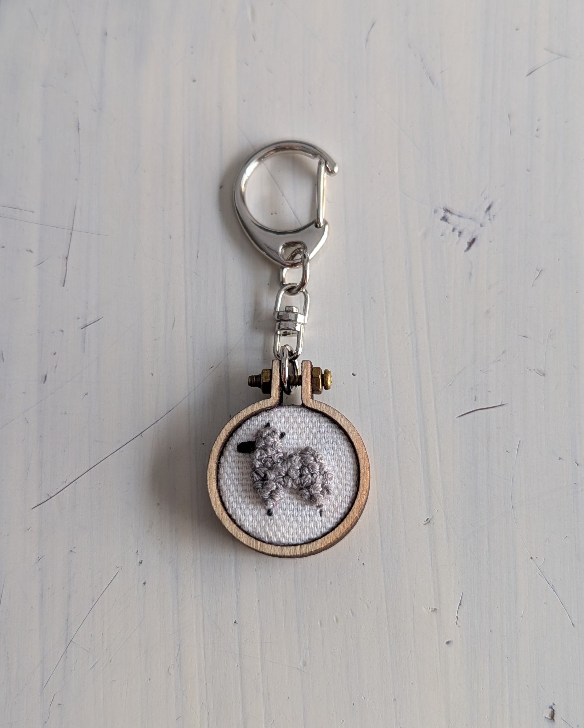 Keychain with embroidered llama design on a light gray background