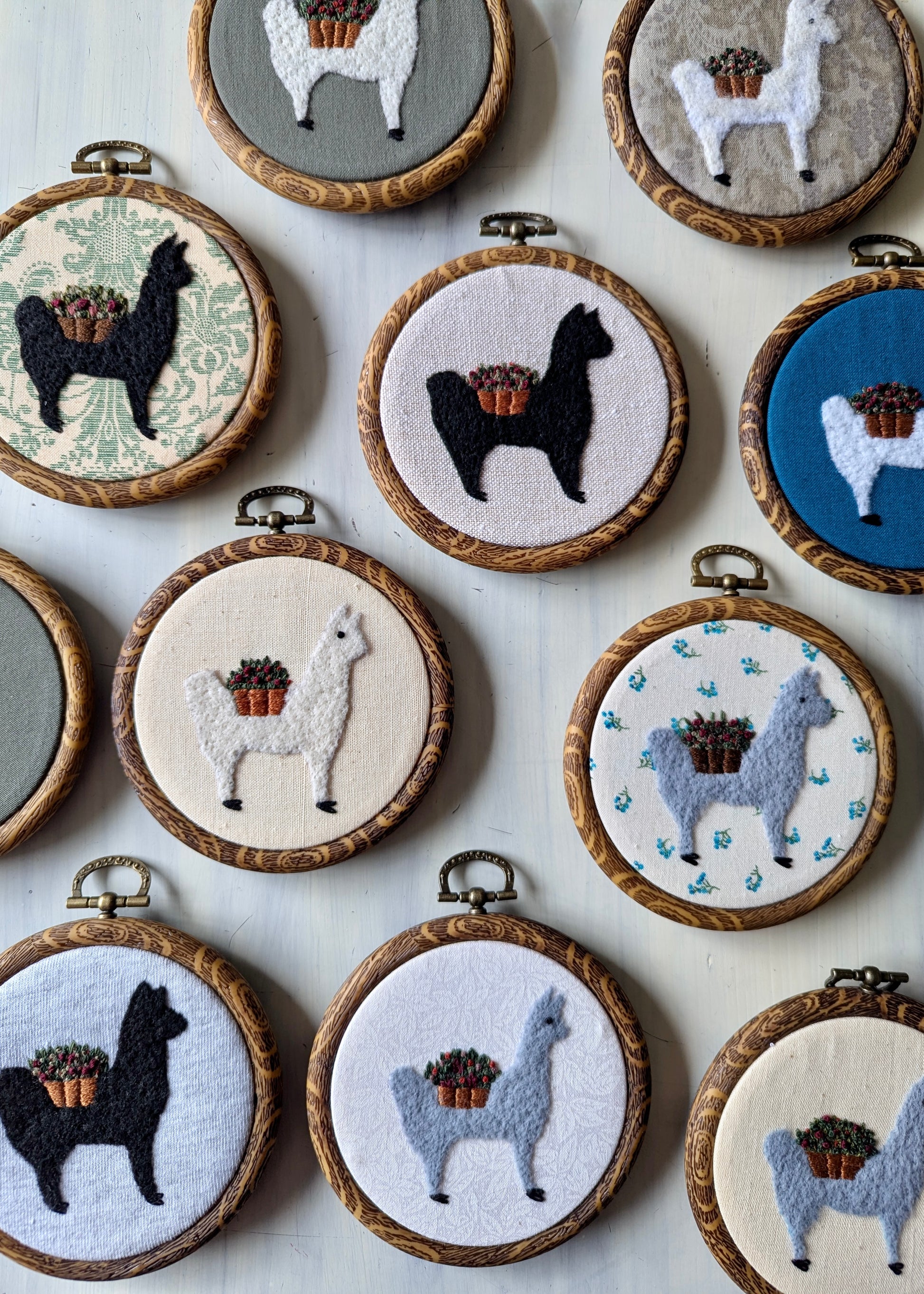 Collection of embroidered hoop art featuring llamas on a light background