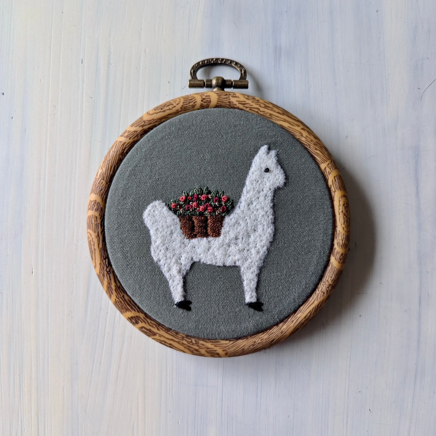 White alpaca wearing a flower basket set on an olive green background