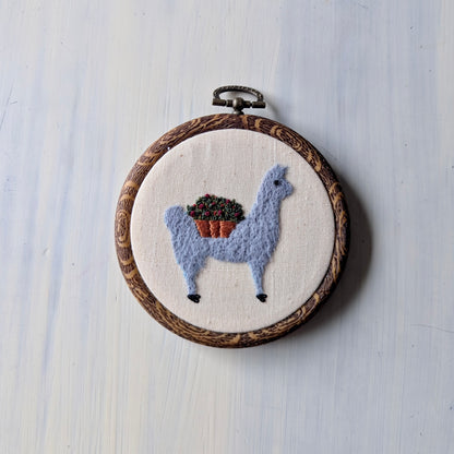 Embroidery hoop with a llama design on a light wooden surface