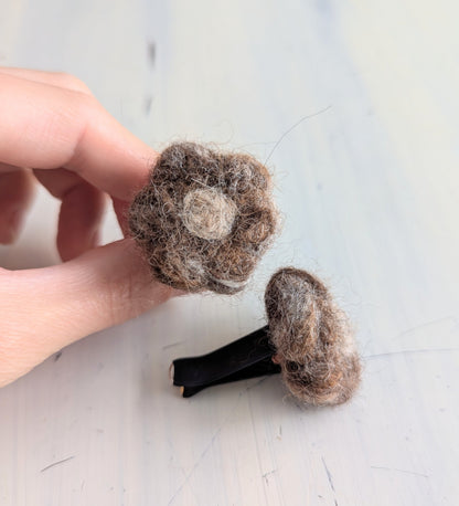Holding a felted car vent air freshener in the shape of a brown flower