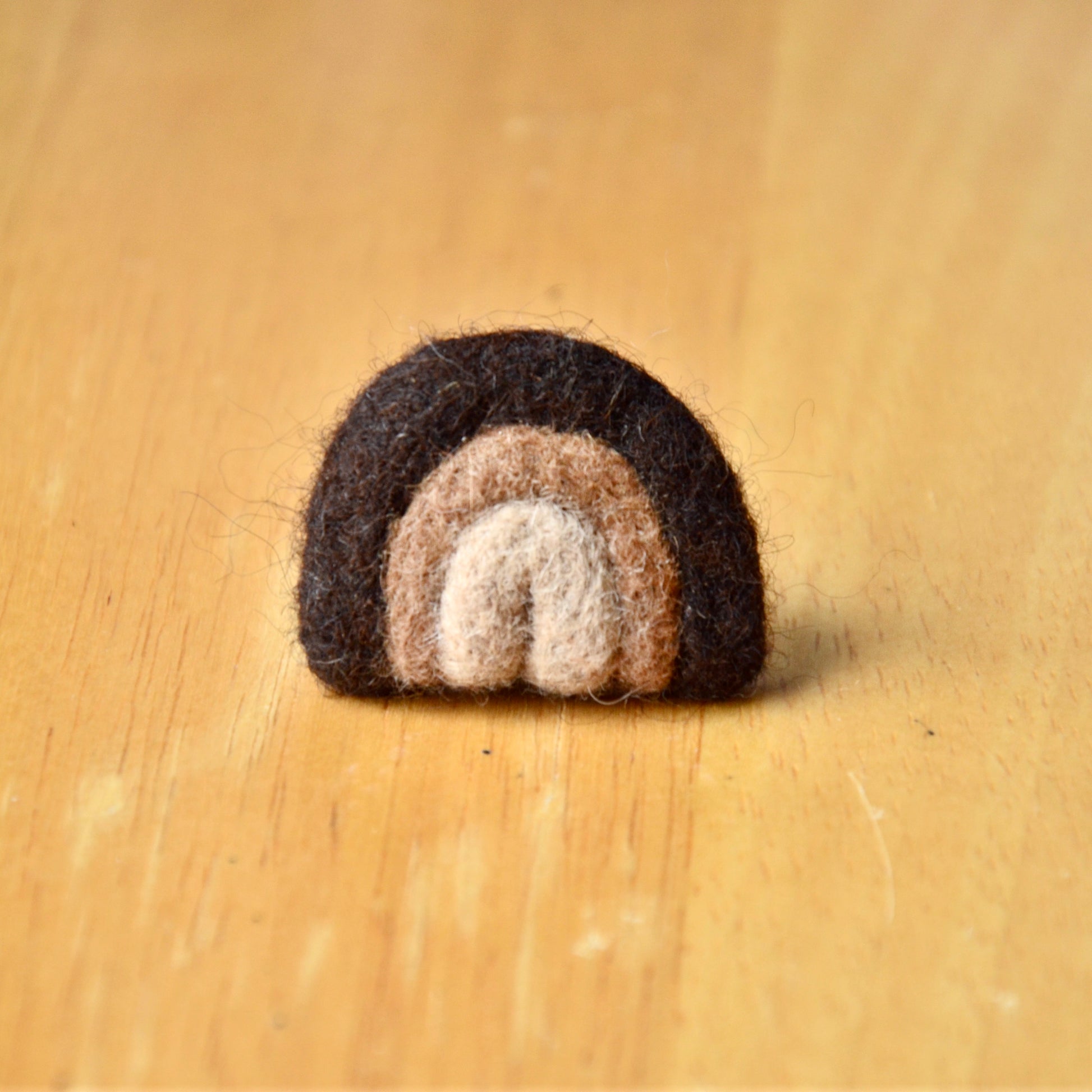 Needle felt air freshener in the shape of a dark brown rainbow
