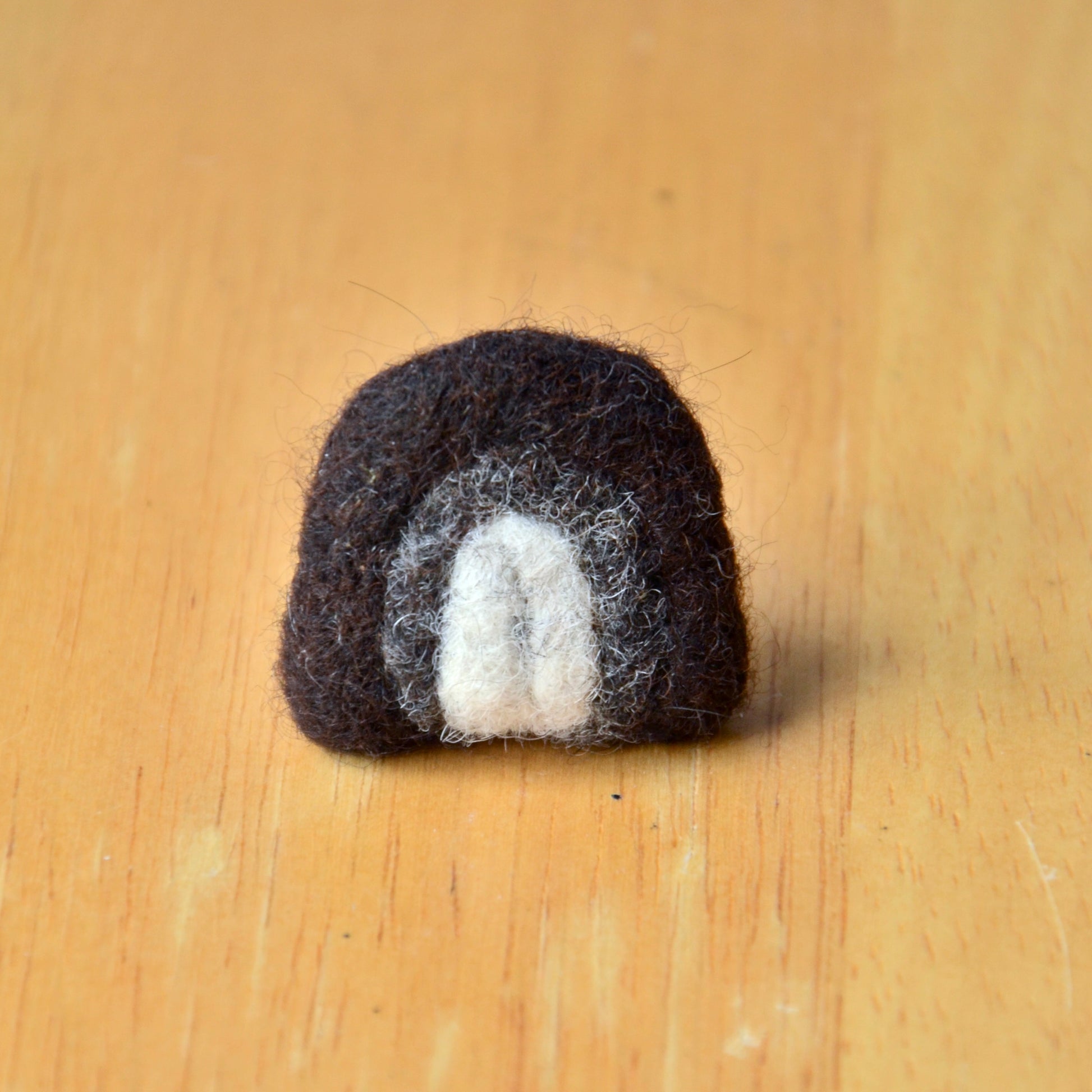 Needle felt air freshener in the shape of a dark grey rainbow