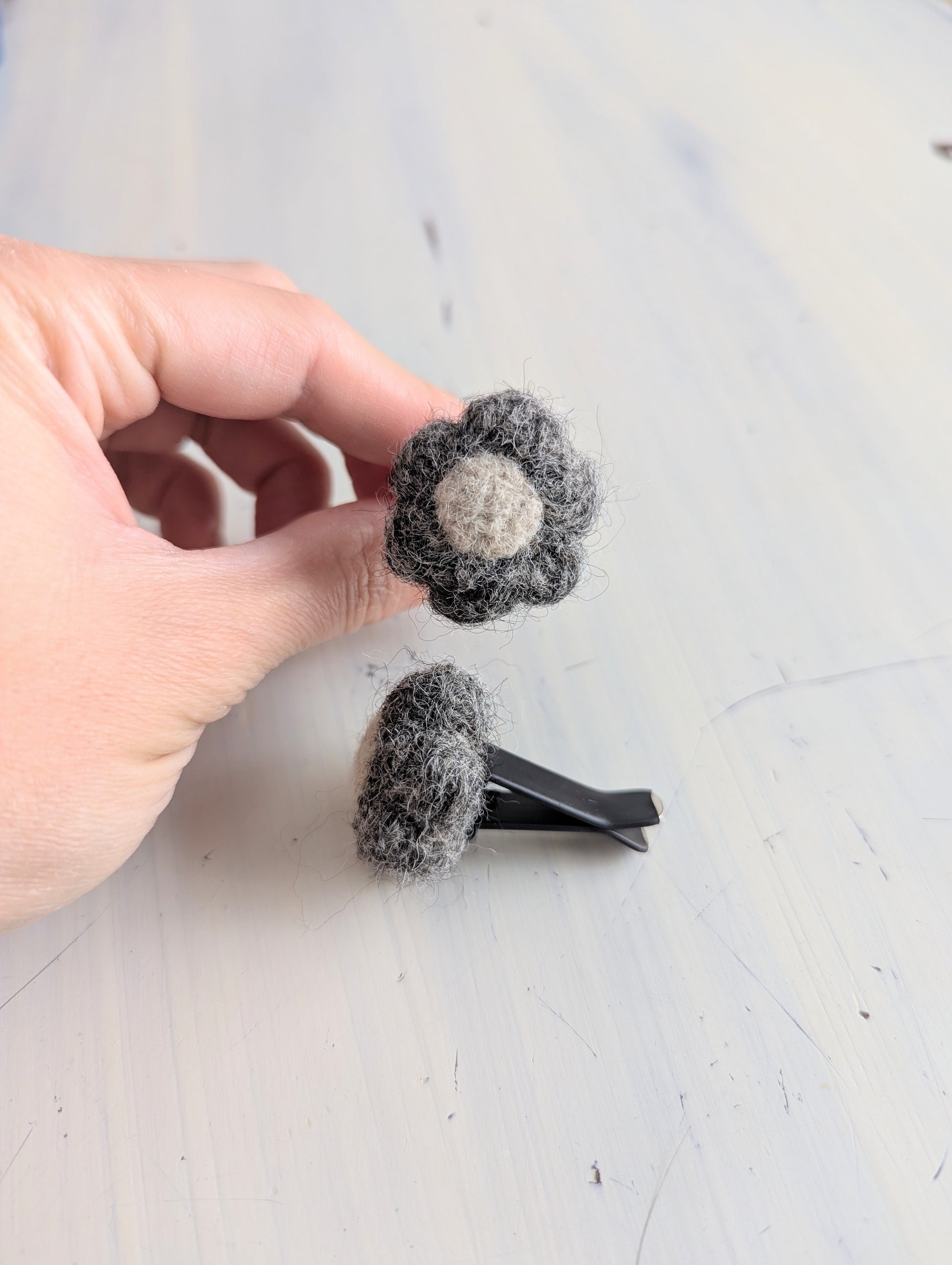 Holding a felted car vent air freshener in the shape of a brown flower