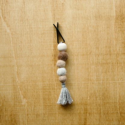 Felted air freshener round tassles over a wooden background
