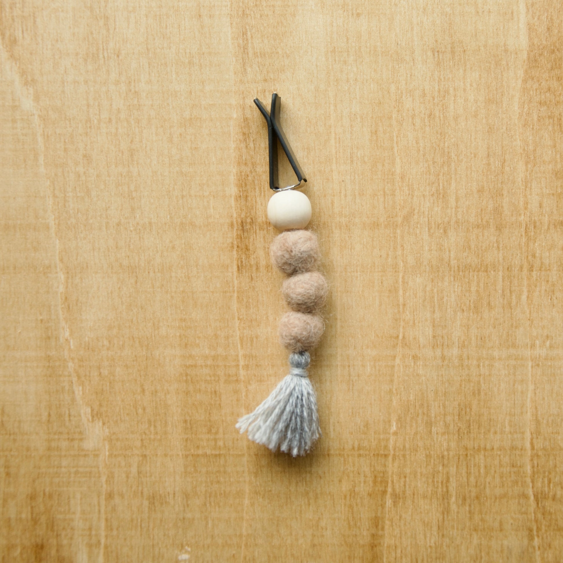 Felted air freshener round tassles over a wooden background