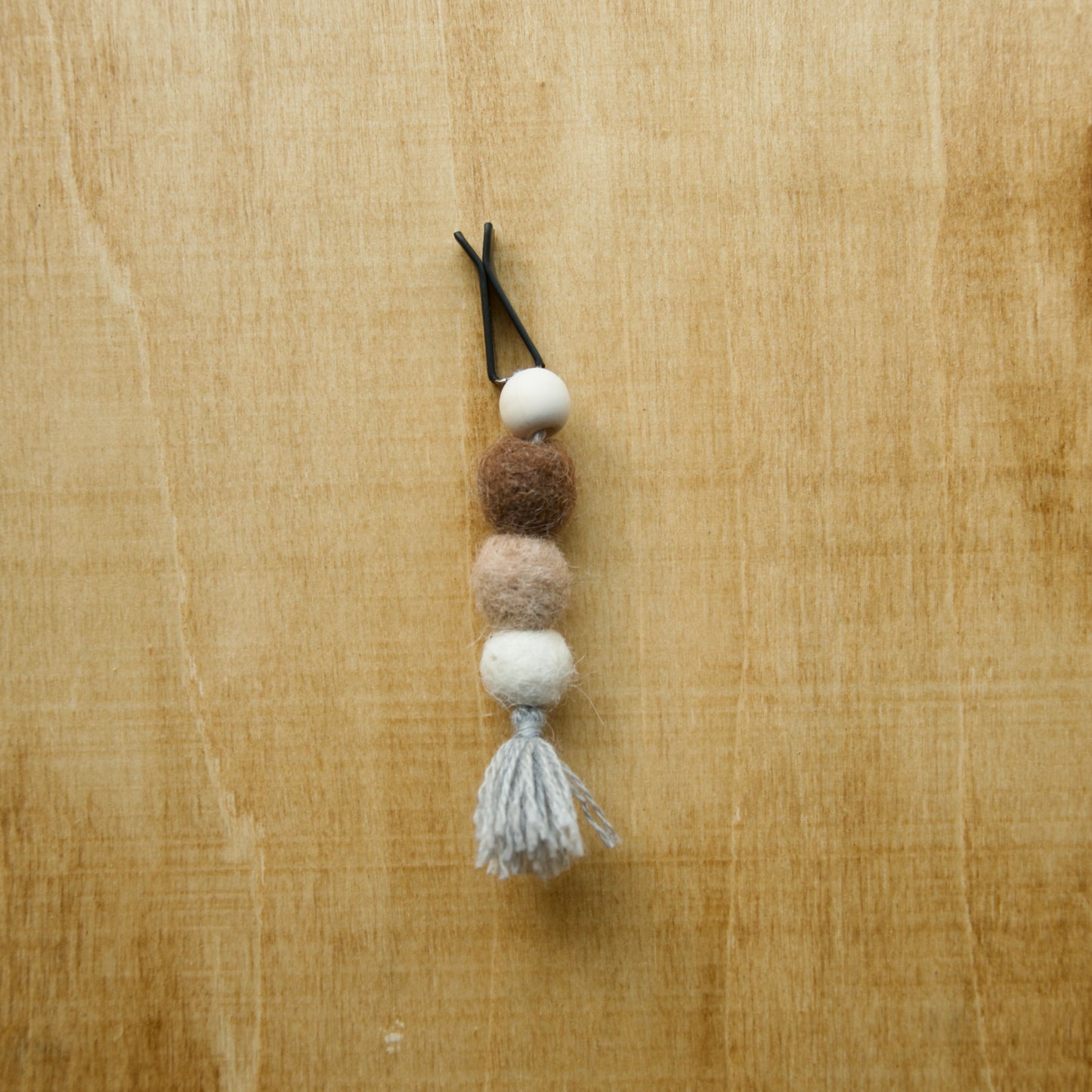 Felted air freshener round tassles over a wooden background