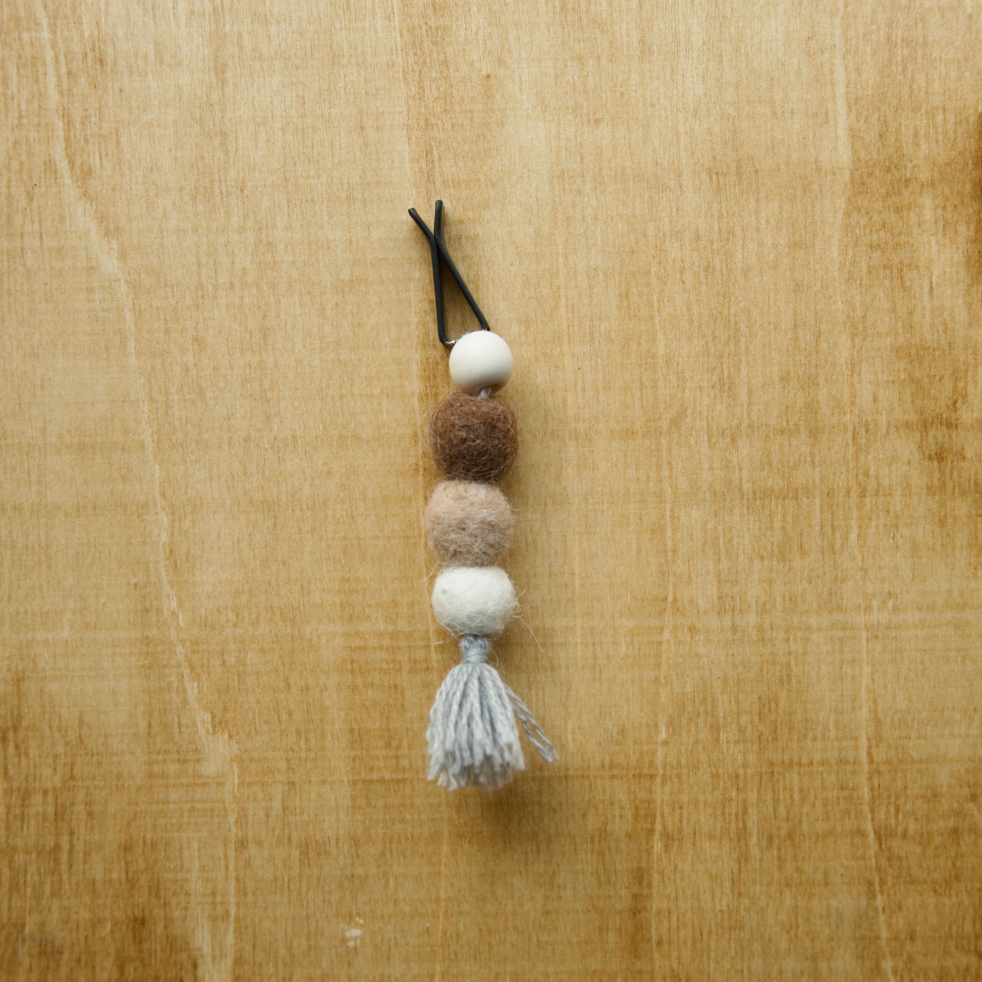 Felted air freshener round tassles over a wooden background