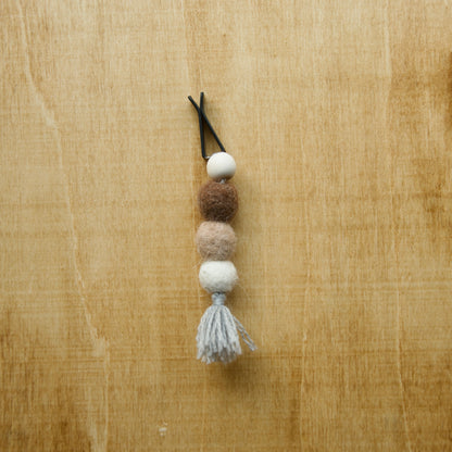 Felted air freshener round tassles over a wooden background