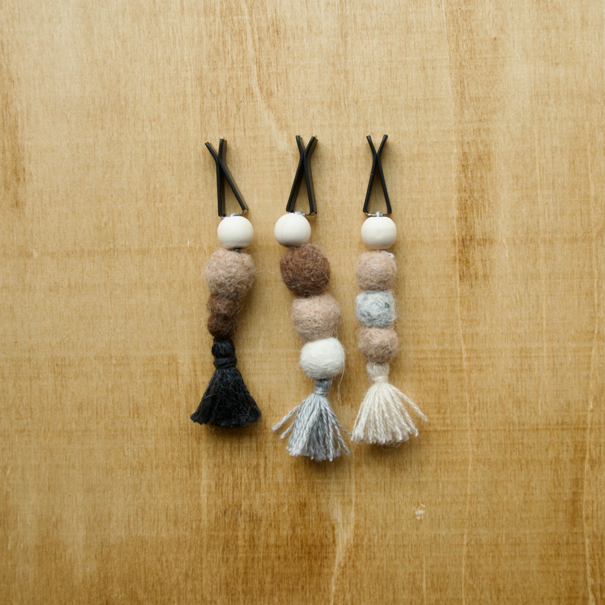 Felted air freshener round tassles over a wooden background