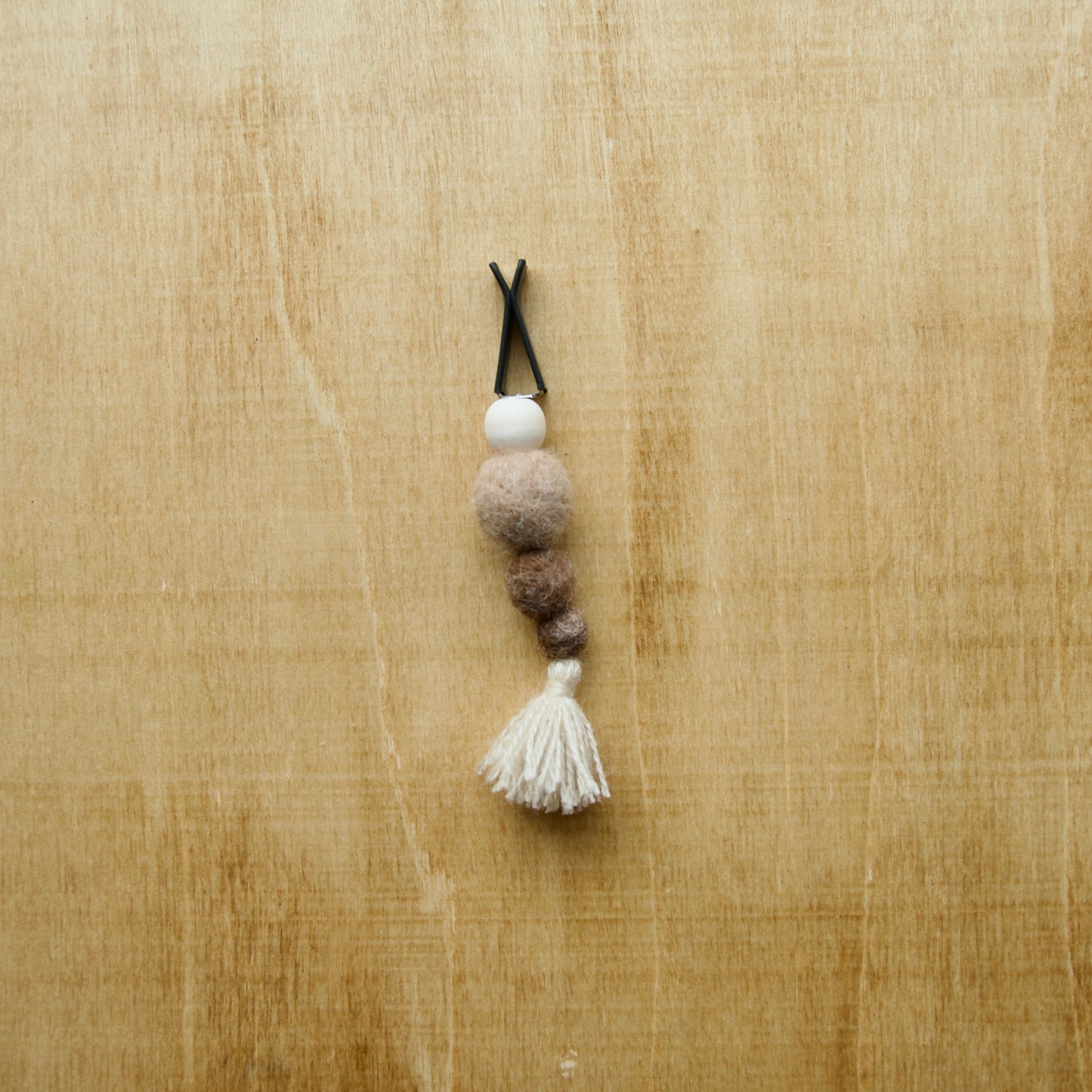 Felted air freshener tassle over a wooden background