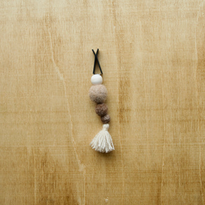 Felted air freshener tassle over a wooden background
