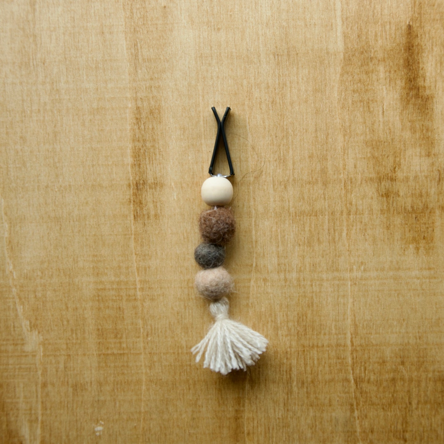 Felted air freshener tassle over a wooden background
