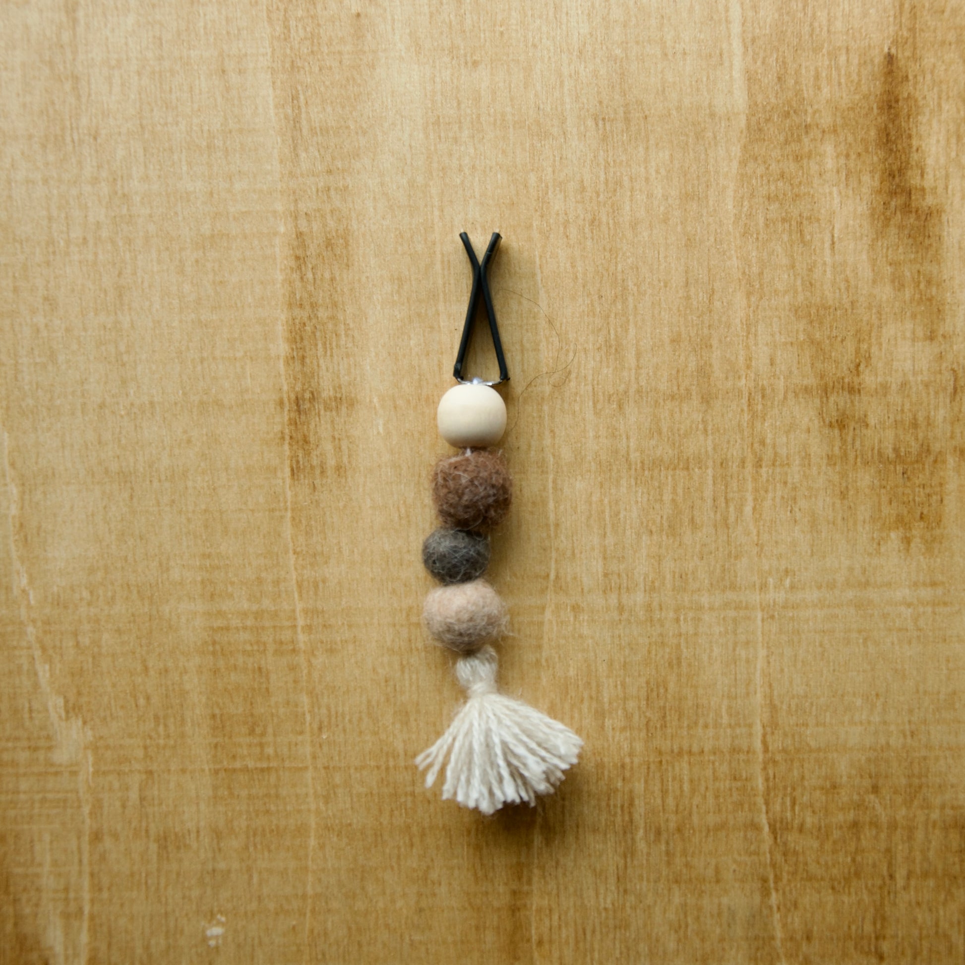 Felted air freshener tassle over a wooden background