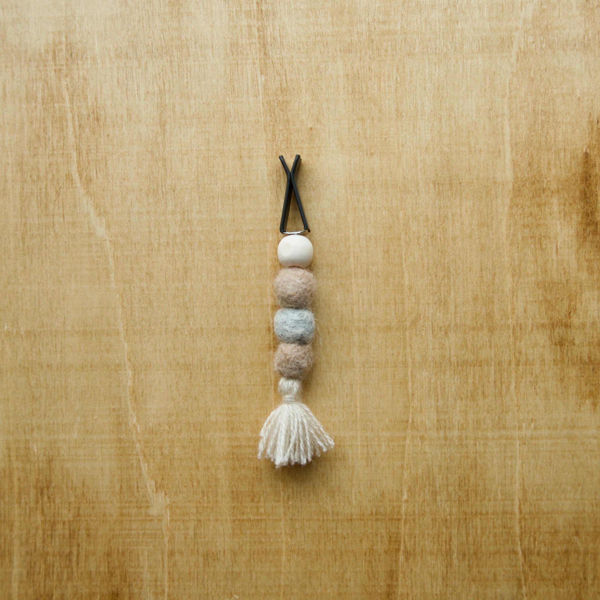 Felted air freshener round tassles over a wooden background