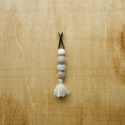 Felted air freshener round tassles over a wooden background