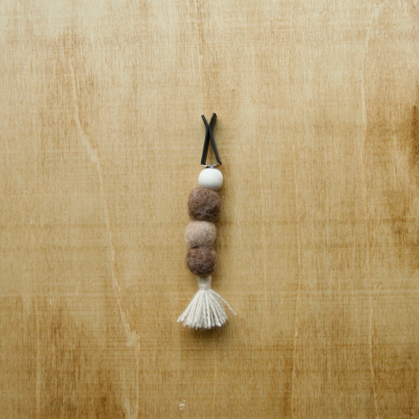 Needle felted air freshener tassle over a wooden background