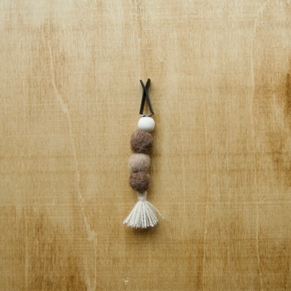 Needle felted air freshener tassle over a wooden background