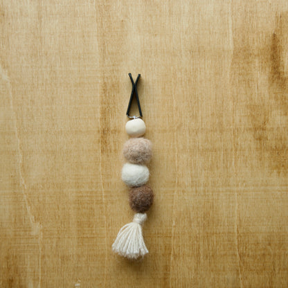 Felted air freshener tassle over a wooden background