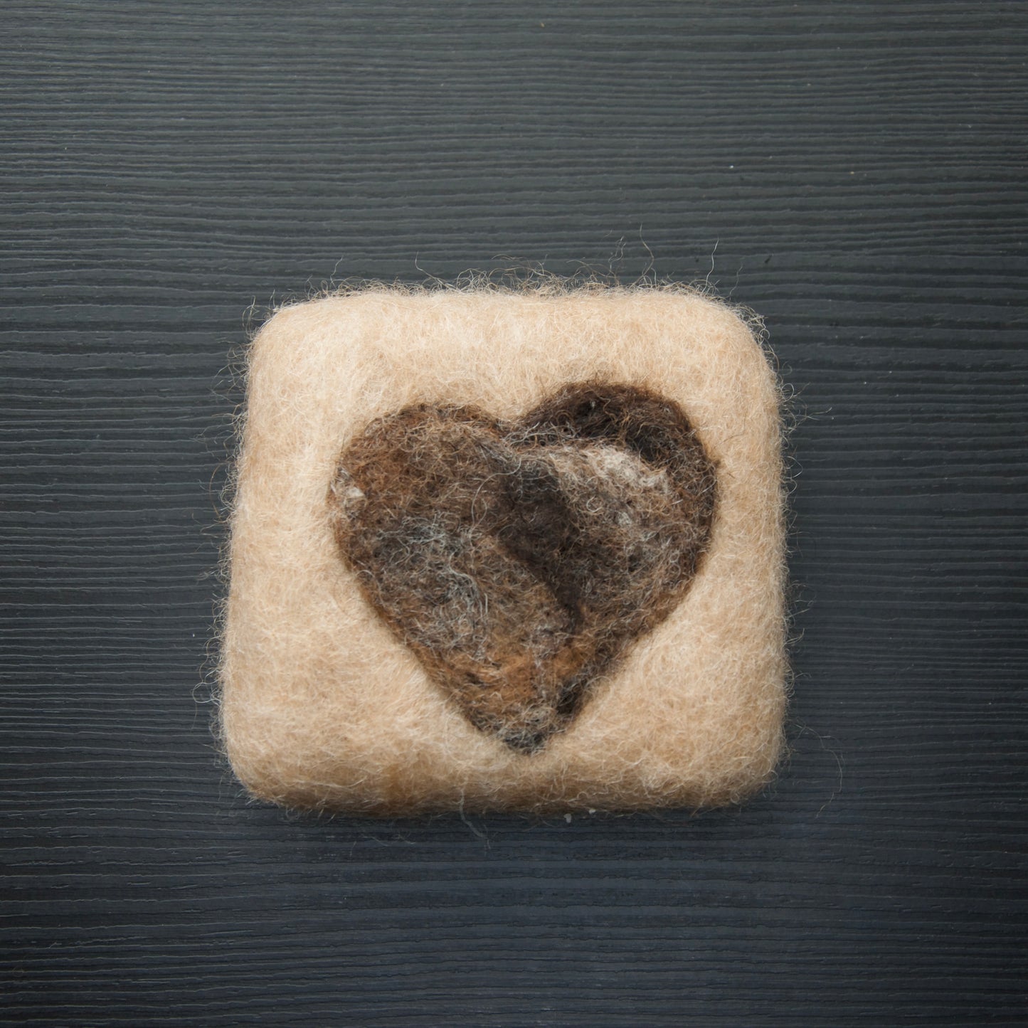 A felted soap bar shaped like a heart on a dark background.