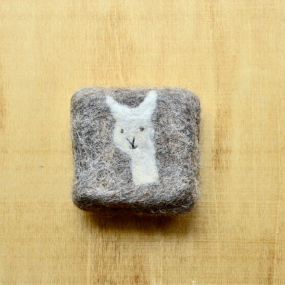 A square felted soap bar on a wooden surface