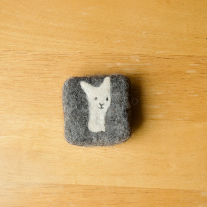 A square felted soap bar on a wooden surface