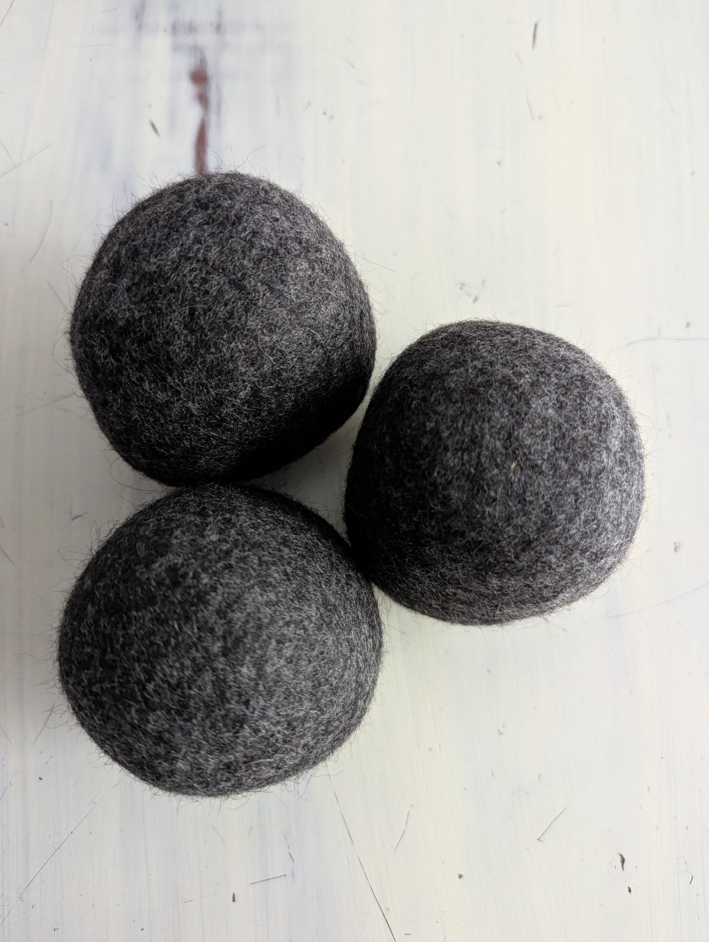 Three gray felt dryer balls on a white surface