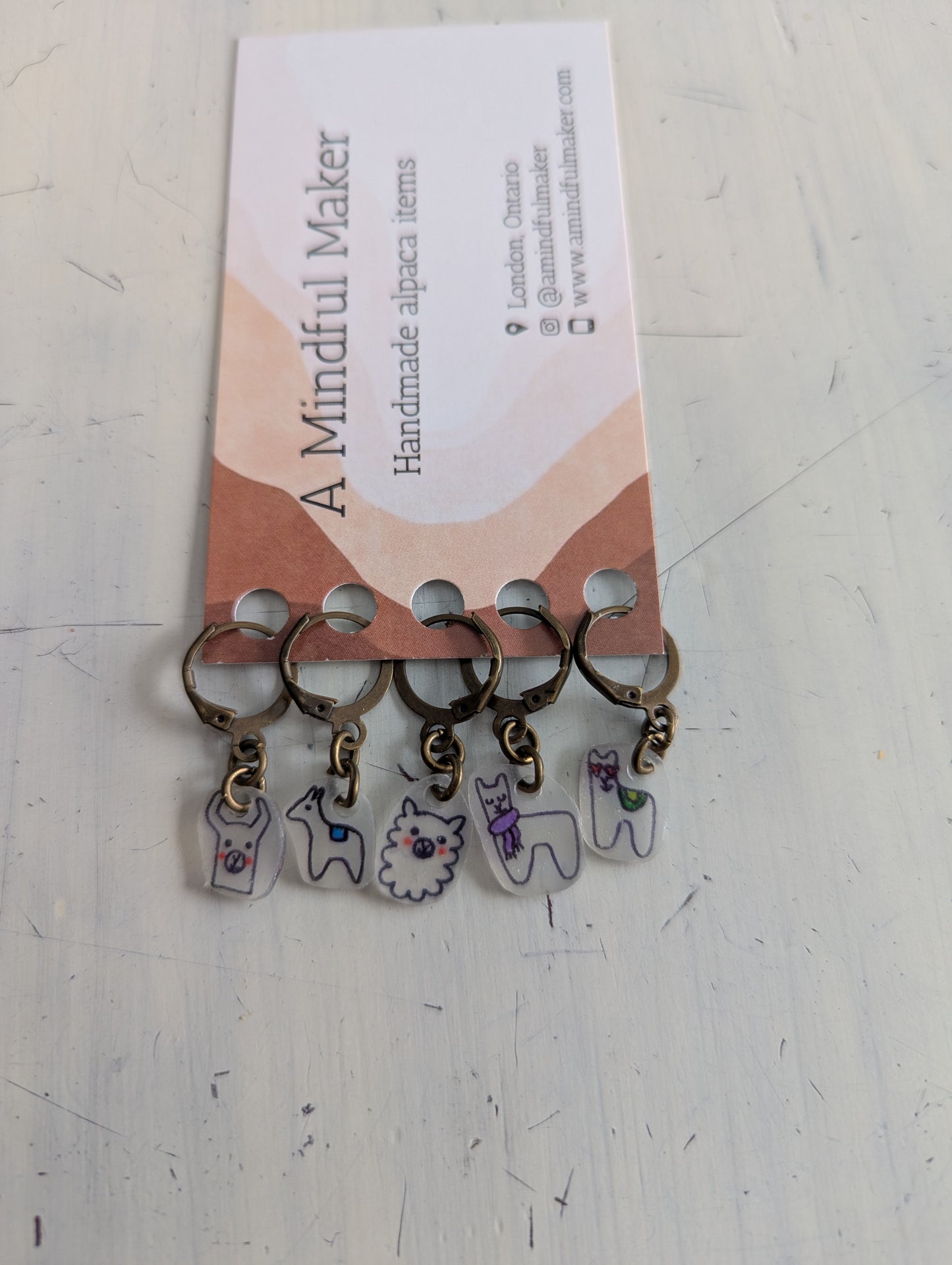 Set of keychains with alpaca charms on a card labeled 'A Mindful Maker' on a white surface.