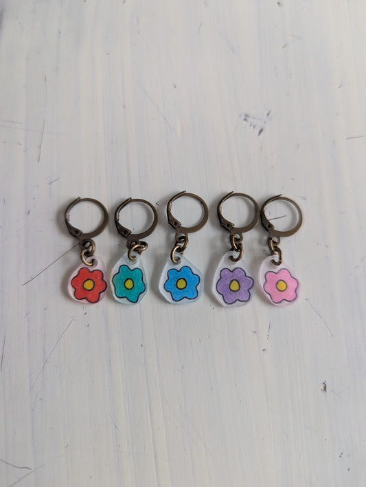 Five floral keychains on a white wooden surface