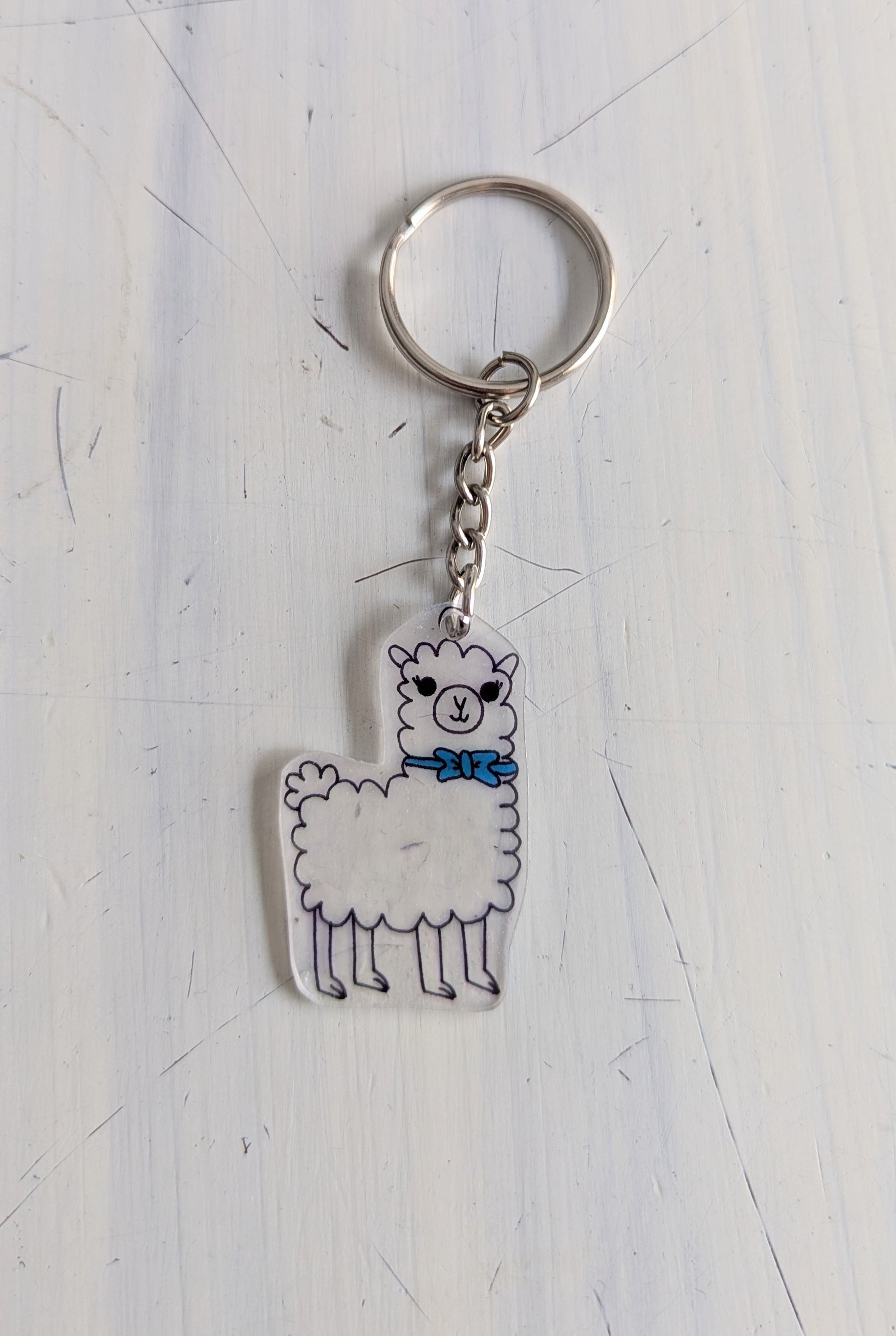 Keychain with a llama design on a light gray surface