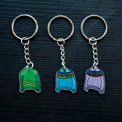 A collection of colorful hand-stitched keychains made from recycled plastic, displayed on a dark surface.