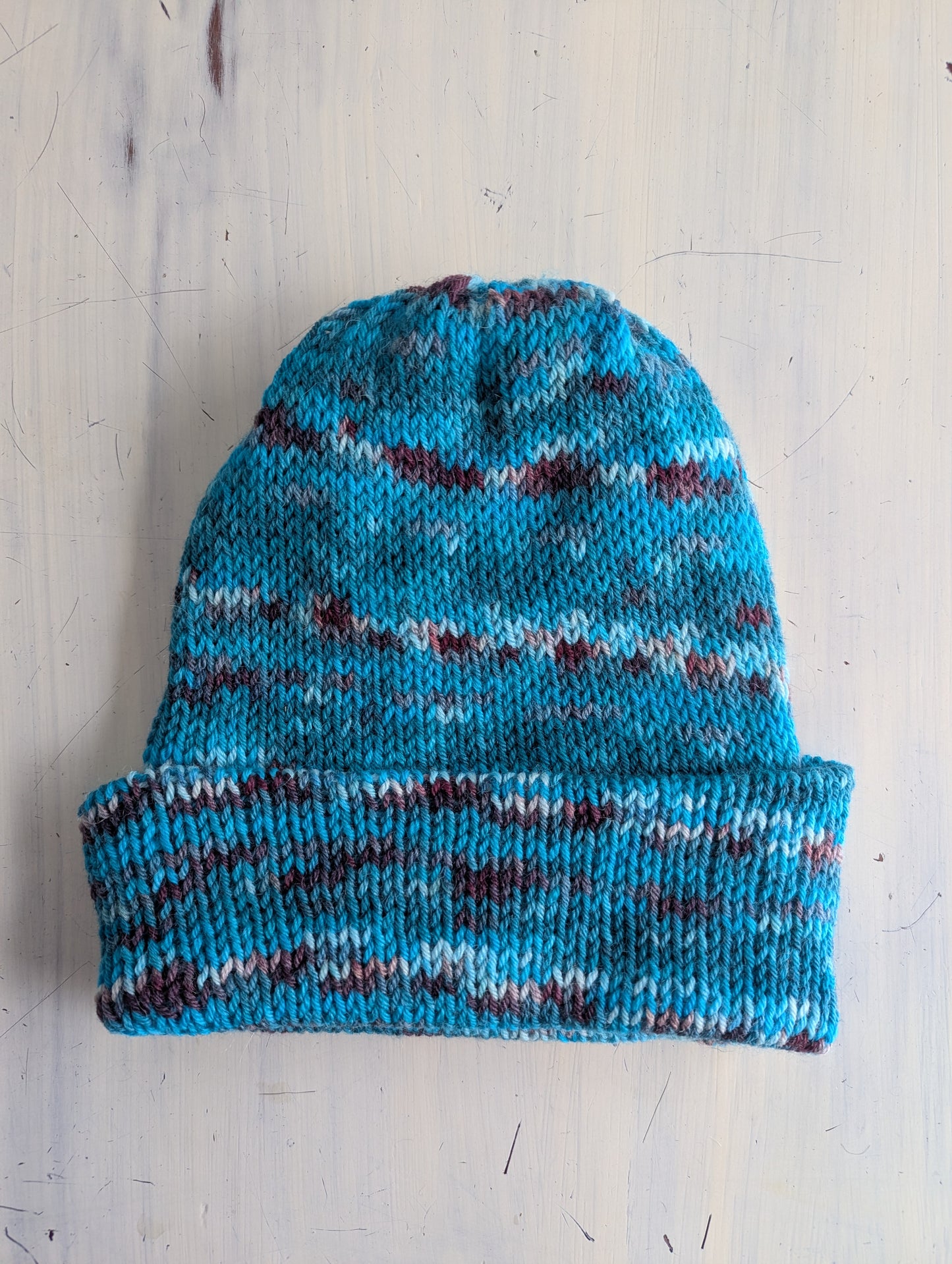 Knitted beanie with blue and multicolor pattern on a light wooden surface
