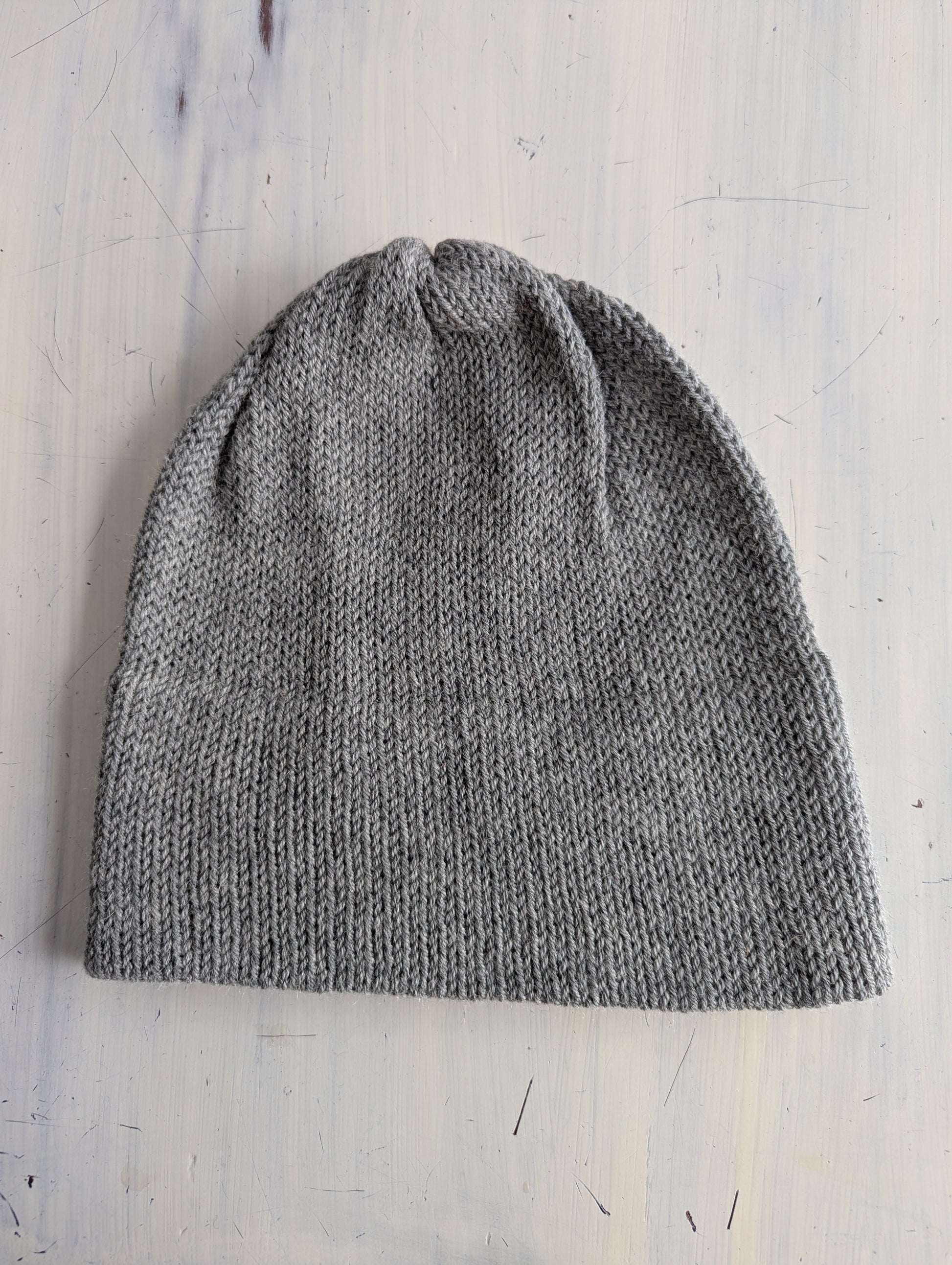 Gray knit beanie on a light wooden surface