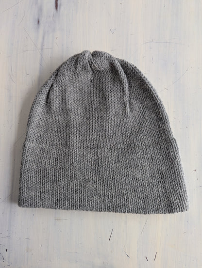 Gray knit beanie on a light wooden surface