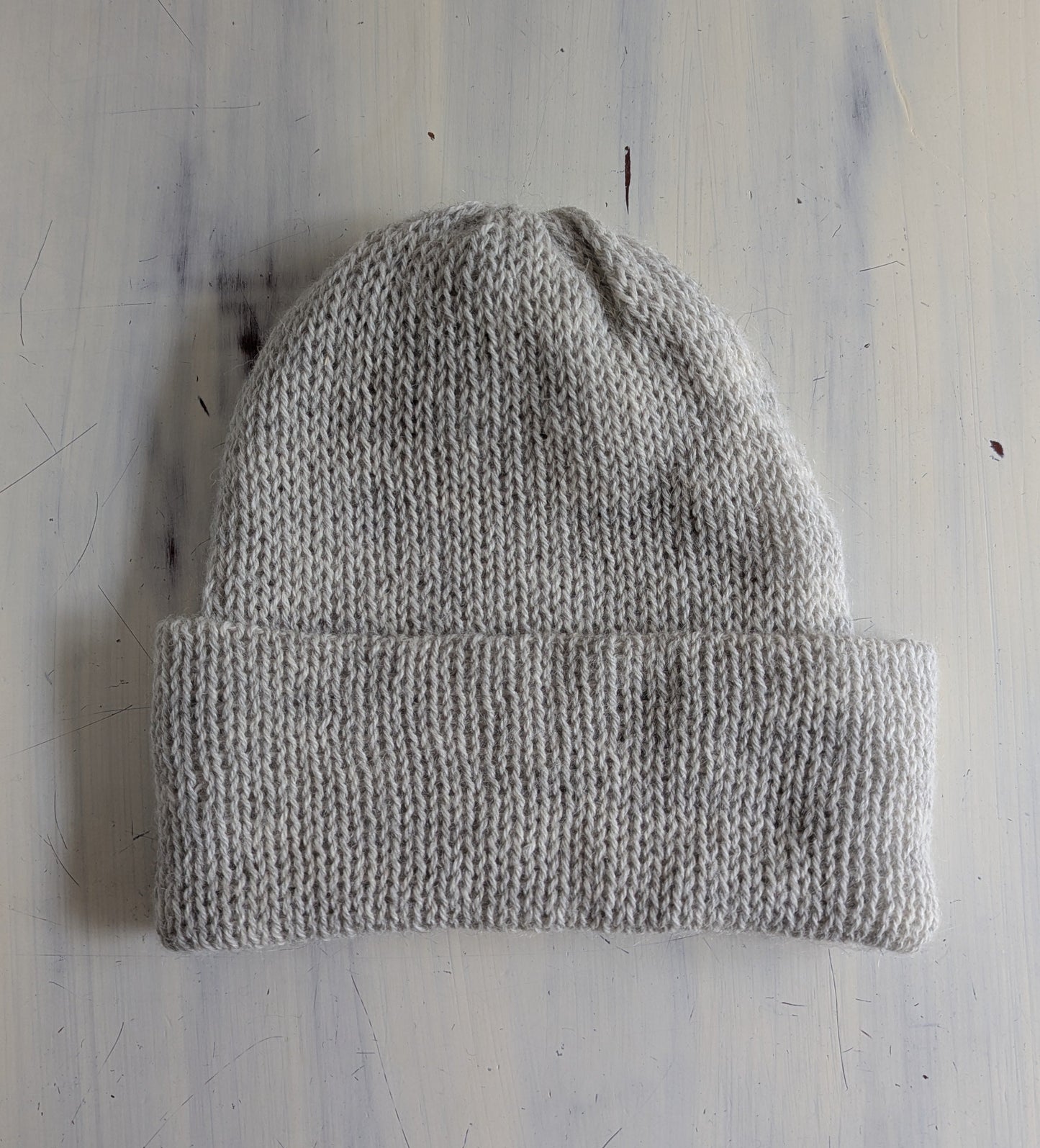 Gray knit beanie on a light wooden surface