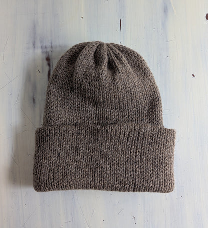 Brown knit beanie on a light blue textured background