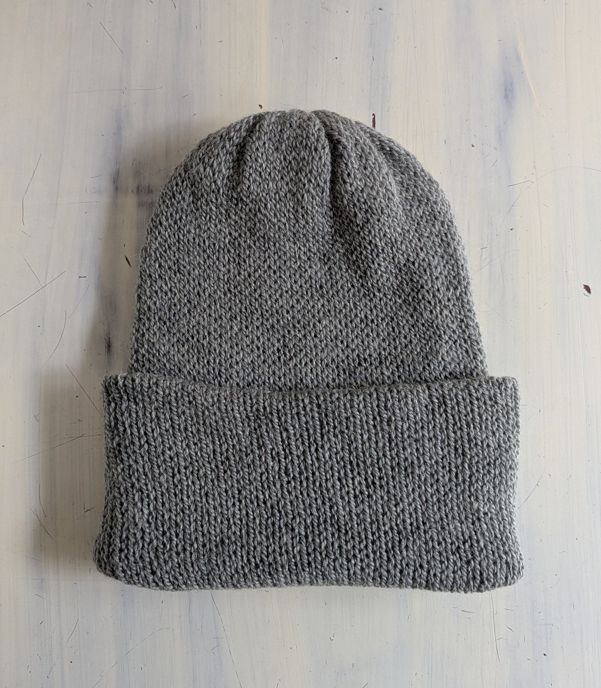Gray knit beanie on a light blue textured surface