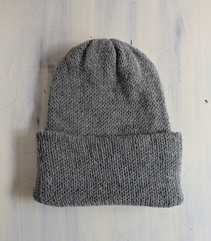 Gray knit beanie on a light blue textured surface