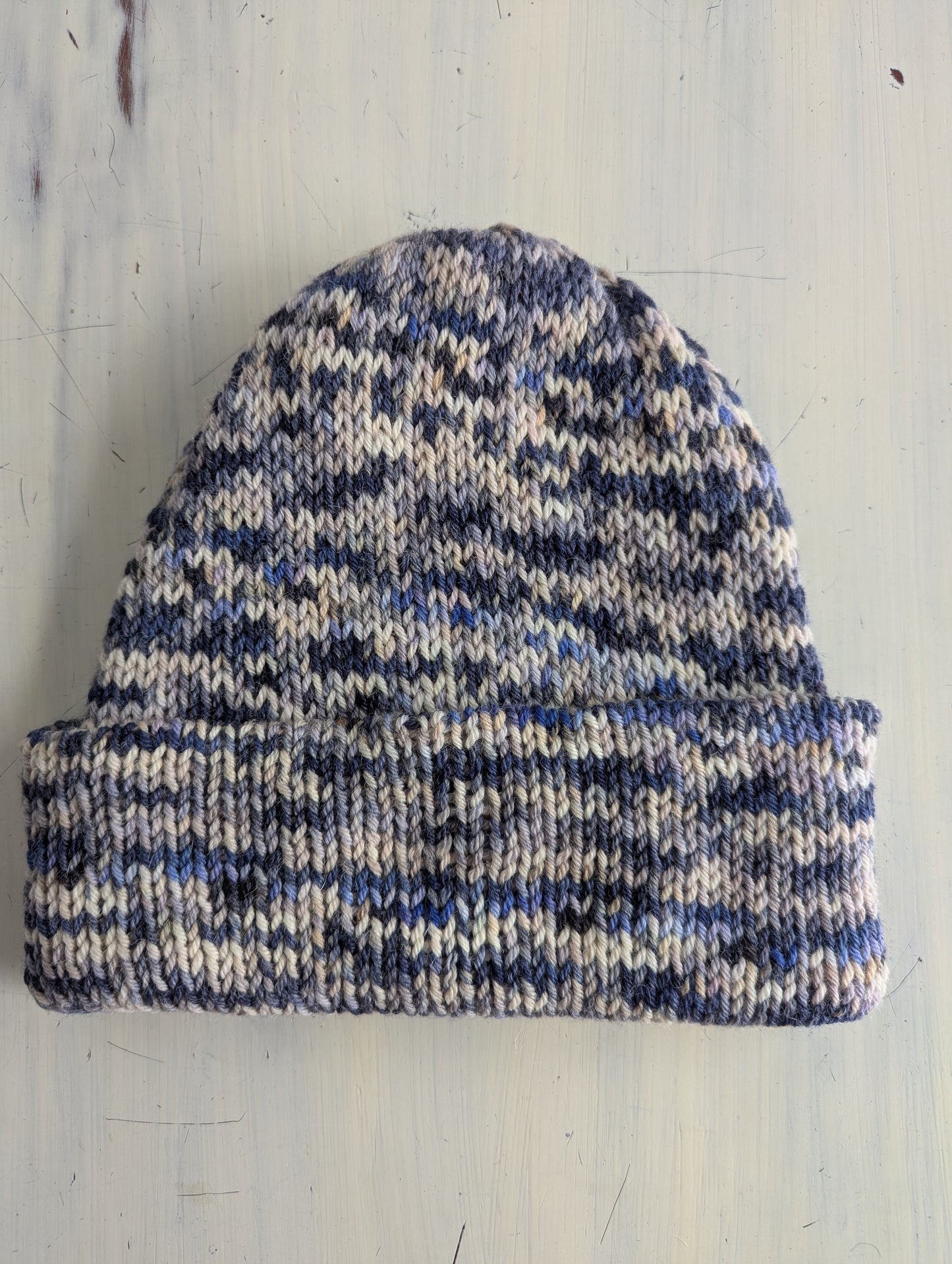 Knitted beanie with blue and white pattern on a light wooden surface