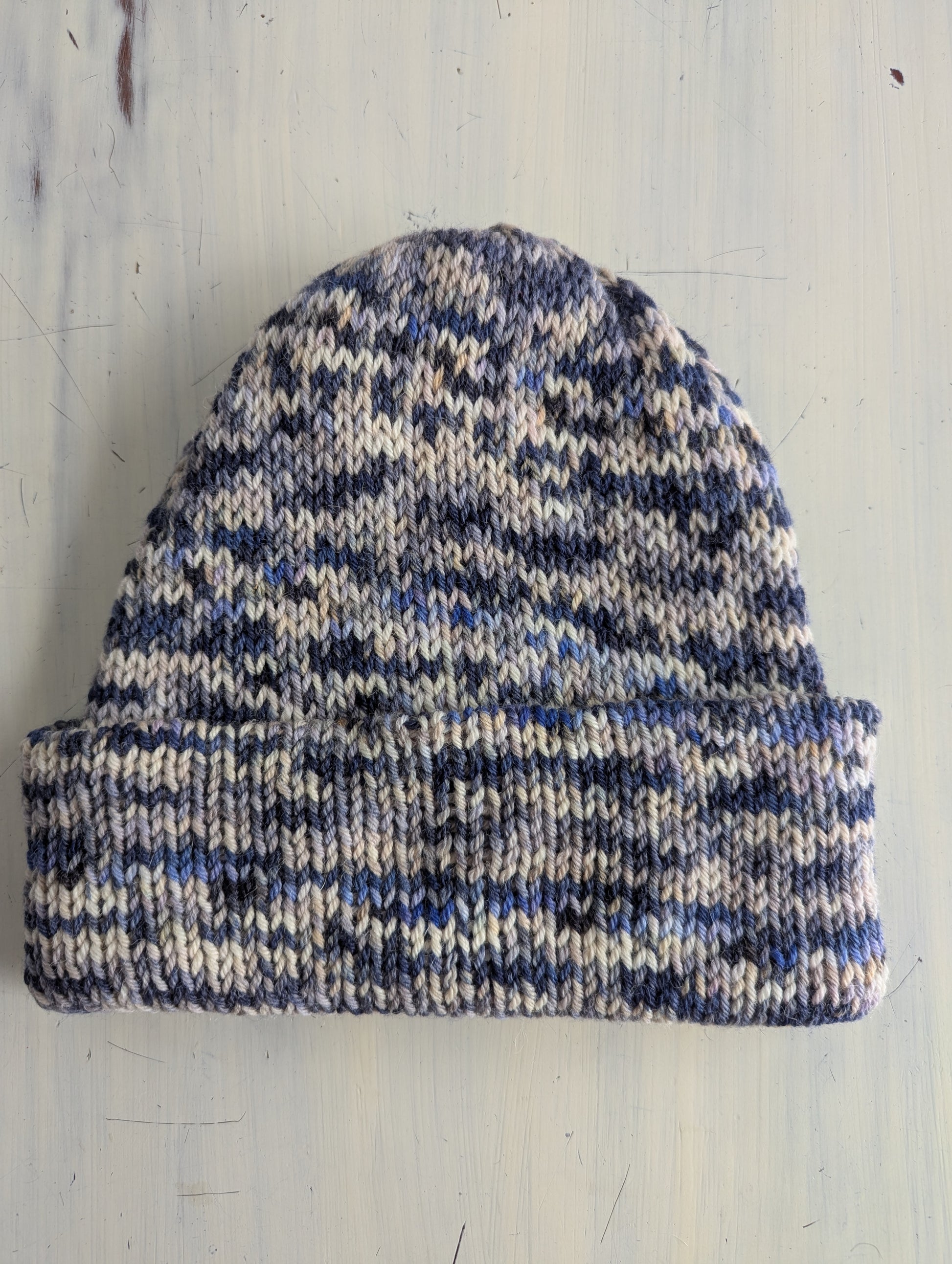 Knitted beanie with blue and white pattern on a light wooden surface