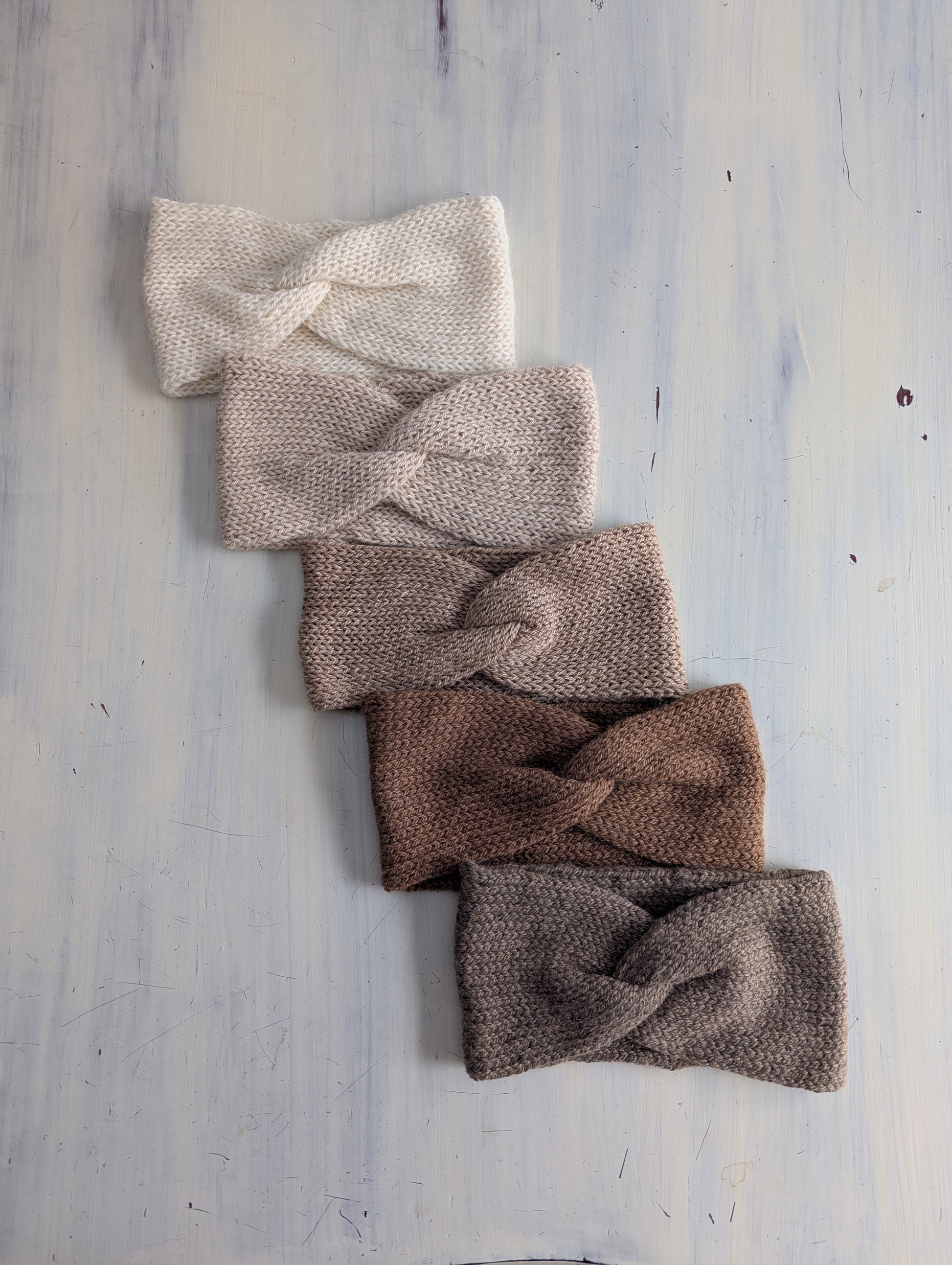 Set of five knitted headbands in various colors on a light wooden surface