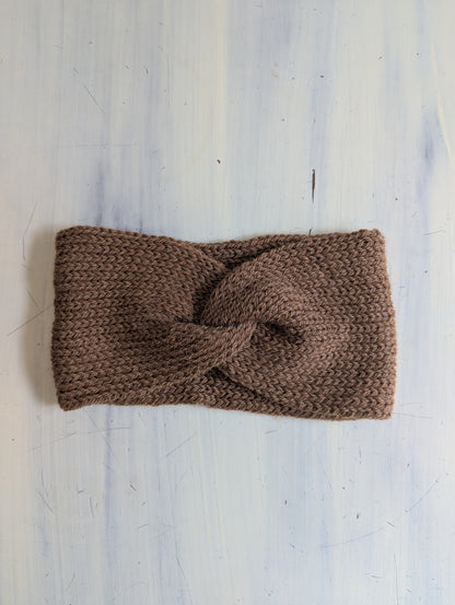 Brown knitted headband on a light grey textured background